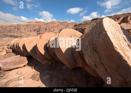 Colonne in rovina in strada colonnata contro le tombe nabatee nell'antica città di Petra, Giordania, patrimonio dell'umanità dell'UNESCO dal 1985 Foto Stock