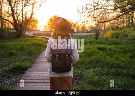 Giovane donna che indossa un cappello che cammina sul sentiero nel parco Foto Stock