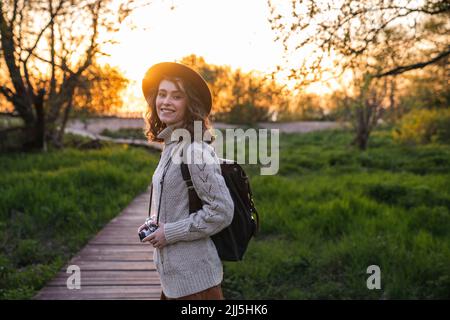 Donna felice con macchina fotografica in piedi nel parco Foto Stock