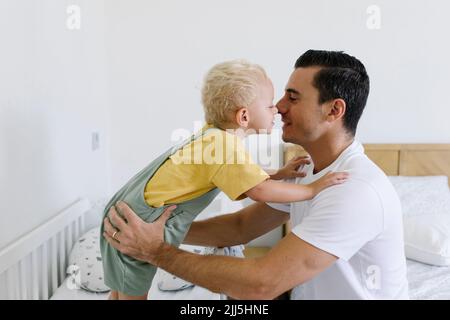 Uomo che sfrega il naso con il figlio a letto a casa Foto Stock