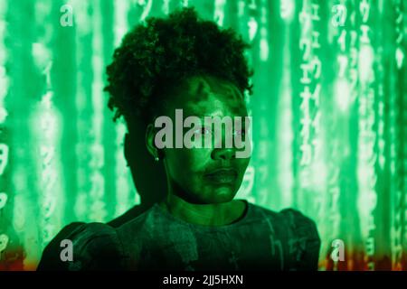 Codice digitale che cade su una donna con acconciatura Afro di fronte al muro Foto Stock