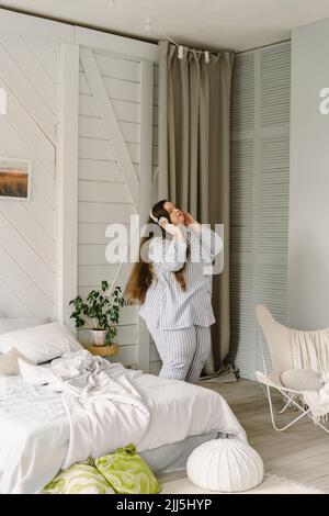 Donna che ascolta la musica con le cuffie wireless a casa Foto Stock