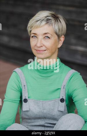 Donna matura sorridente con capelli biondi corti Foto Stock