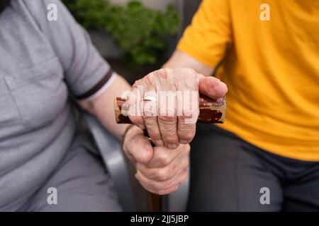 Mani di coppia senior che tengono bastone da passeggio Foto Stock