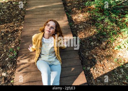 Giovane donna che si rilassa sul sentiero nel bosco Foto Stock