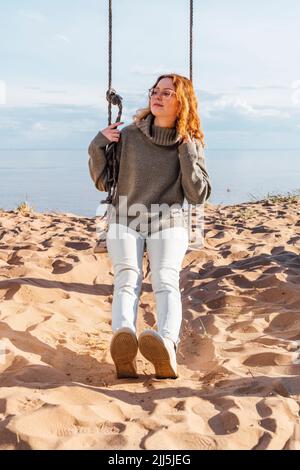 Giovane donna seduta su swing a beach Foto Stock