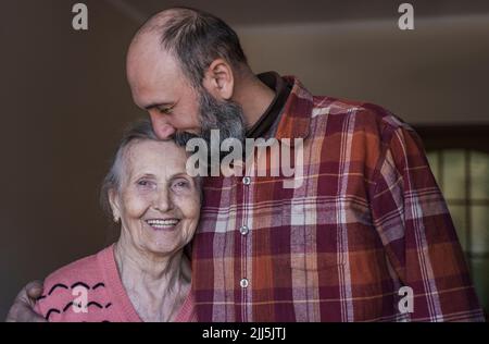 Uomo maturo che bacia la donna anziana a casa Foto Stock