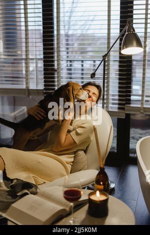 Cane che lecca il volto della donna in bagno a casa Foto Stock