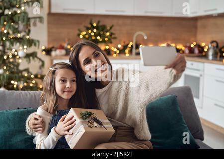 Donna felice che prende selfie con la figlia attraverso lo smartphone a casa Foto Stock