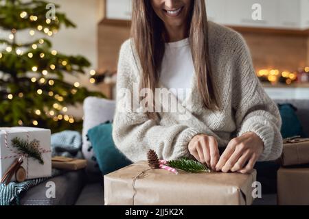 Donna sorridente che avvolge il regalo a casa Foto Stock