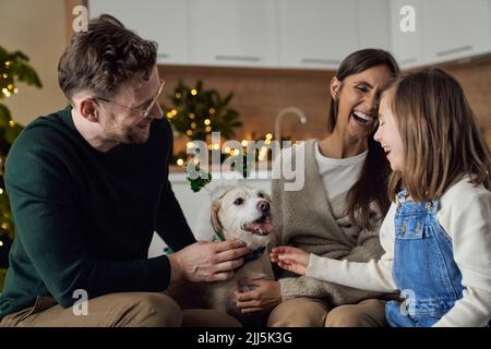 Famiglia felice con il cane godendo il tempo di Natale insieme a casa Foto Stock