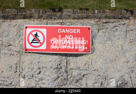 Pericolo No Trespassing segno sul muro lungo la ferrovia a Dawlish, South Devon. Foto Stock