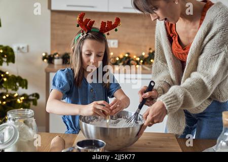 Madre con figlia mescolare la pasta biscotto in cucina Foto Stock