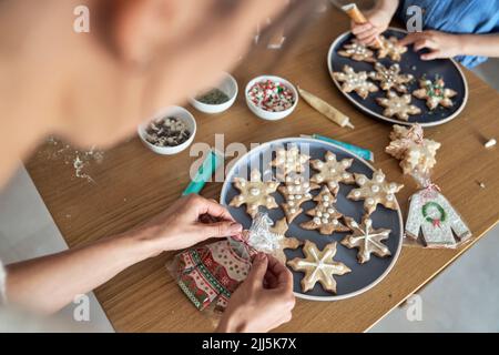 Donna che confezionano biscotti fatti in casa di pan di zenzero da ragazza che decorano a casa Foto Stock