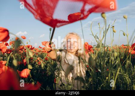 Ragazza felice che gioca con la rete della farfalla in campo papavero Foto Stock