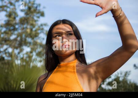 La giovane donna protegge il viso dalla luce del sole Foto Stock