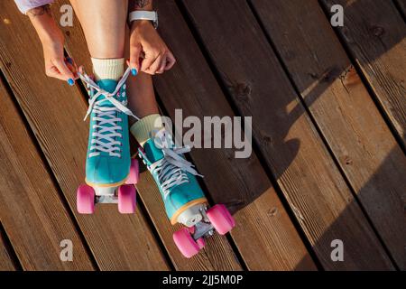 Mani di donna che legano pizzo di roller skate in giornata di sole Foto Stock