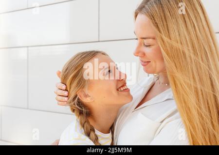 Felice madre e figlia in piedi di fronte al muro Foto Stock