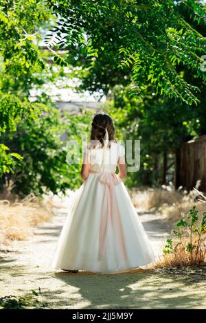 Ragazza vestito di comunione camminare sul sentiero in foresta Foto Stock