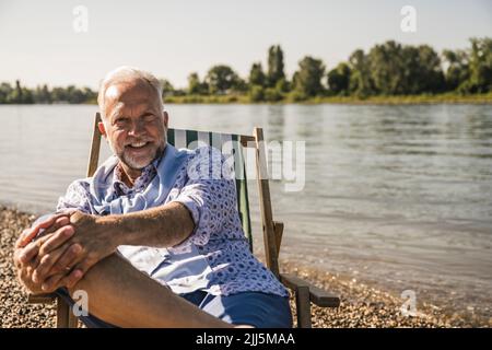 Uomo anziano sorridente in riva al fiume Foto Stock