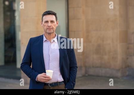 Uomo d'affari sicuro che tiene la tazza usa e getta Foto Stock