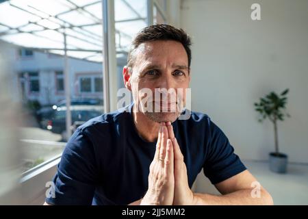 Uomo d'affari maturo sorridente con le mani afferrato in ufficio Foto Stock