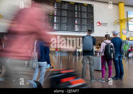 Bruxelles, Belgio. 23rd luglio 2022. L'illustrazione mostra i passeggeri che guardano l'imbarco informazioni sulla partenza del volo nella sala partenze dell'aeroporto di Bruxelles, a Zaventem, sabato 23 luglio 2022. In Belgio sono stati annullati circa 80 voli. Si tratta di voli con equipaggio belga. Gli altri voli partono con un equipaggio da paesi in cui non vi è sciopero. Le ragioni dello sciopero di questo fine settimana sono le stesse dell'azione di fine giugno. I piloti si sentono fraintesi e si aspettano un aumento della retribuzione dopo una resa del 20% durante la crisi della corona. BELGA FOTO NICOLAS MAETE Foto Stock