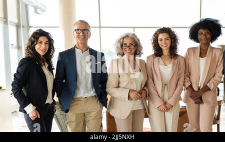 Colleghi di affari multirazziali sicuri che si levano in piedi insieme all'ufficio Foto Stock