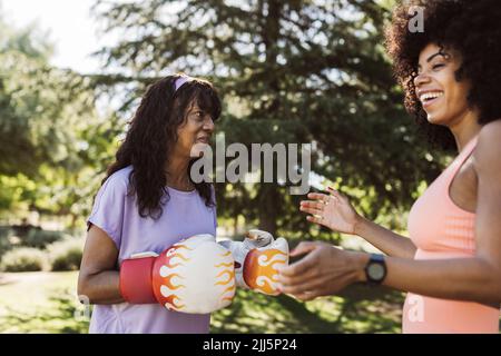 Donna che ride da madre con guanti da boxe nel parco Foto Stock