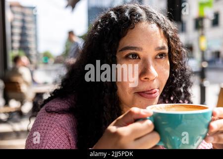 Giovane donna che si gusta un caffè in giornata di sole Foto Stock