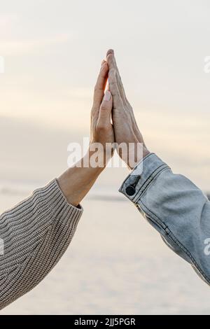 Coppia mani toccanti di fronte al cielo al tramonto Foto Stock