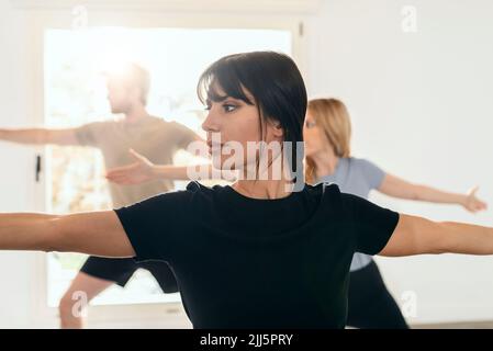Donna che pratica guerriero posa in studio yoga Foto Stock