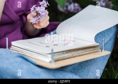 Donna con libro che tiene fiori lilla Foto Stock