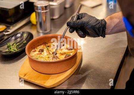 Mano di chef che guarnisce il cibo con pinzette Foto Stock