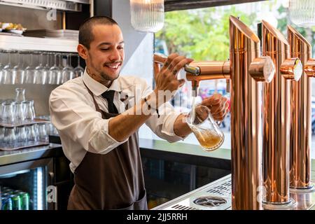 Barista ripieno birra in bicchiere dalla spina al bar Foto Stock