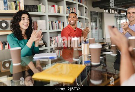 Felice donna d'affari con i colleghi che festeggiano il successo in ufficio Foto Stock