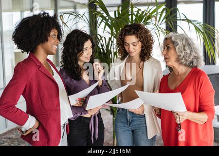 Colleghi di lavoro felici che discutono oltre i documenti in ufficio Foto Stock