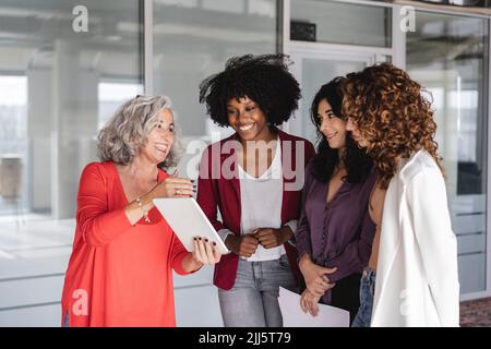 Felice donna d'affari con colleghi che parlano di tablet PC Foto Stock