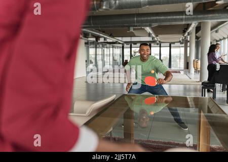 Felice uomo d'affari che gioca a ping pong in ufficio Foto Stock