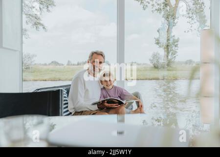 Uomo maturo felice con figlio seduto sul divano a casa Foto Stock