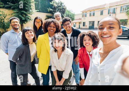 Uomini d'affari sorridenti e donne d'affari che prendono selfie in giornata di sole Foto Stock