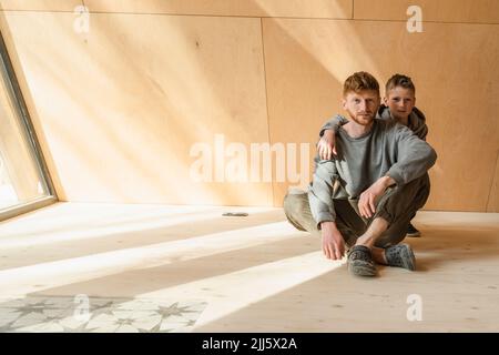 Padre e figlio seduti sul pavimento in legno eco casa Foto Stock