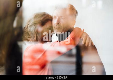 Donna felice che abbraccia l'uomo in un caffè visto attraverso la finestra Foto Stock