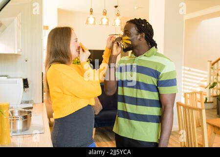 Coppia giocosa che fa i baffi dagli spaghetti non cotti a casa Foto Stock