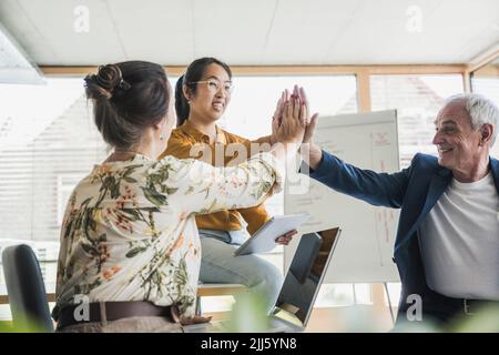 Colleghi di lavoro di successo che si danno cinque alti a vicenda in ufficio Foto Stock
