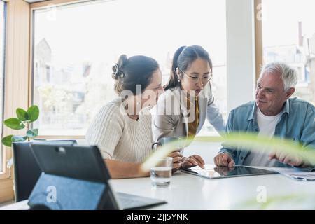 Colleghi di lavoro che parlano di PC tablet in ufficio Foto Stock