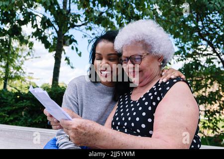 Felice madre e figlia leggere lettera al parco Foto Stock