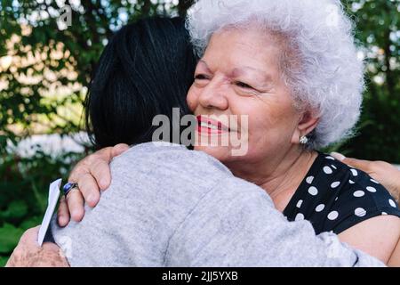 Sorridente madre anziana che abbraccia la figlia nel parco Foto Stock