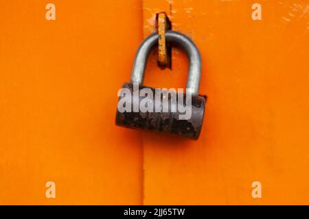 Serratura sulla porta. Serratura in acciaio su cancello arancione. Porta chiusa. Meccanismo di bloccaggio. Foto Stock