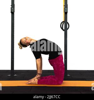 Un addestratore della signora della gioventù sta effettuando la posa di yoga del cammello in una palestra. Ustrasana la posa del cammello per la stimolazione della parte inferiore della schiena e della gola. Foto Stock